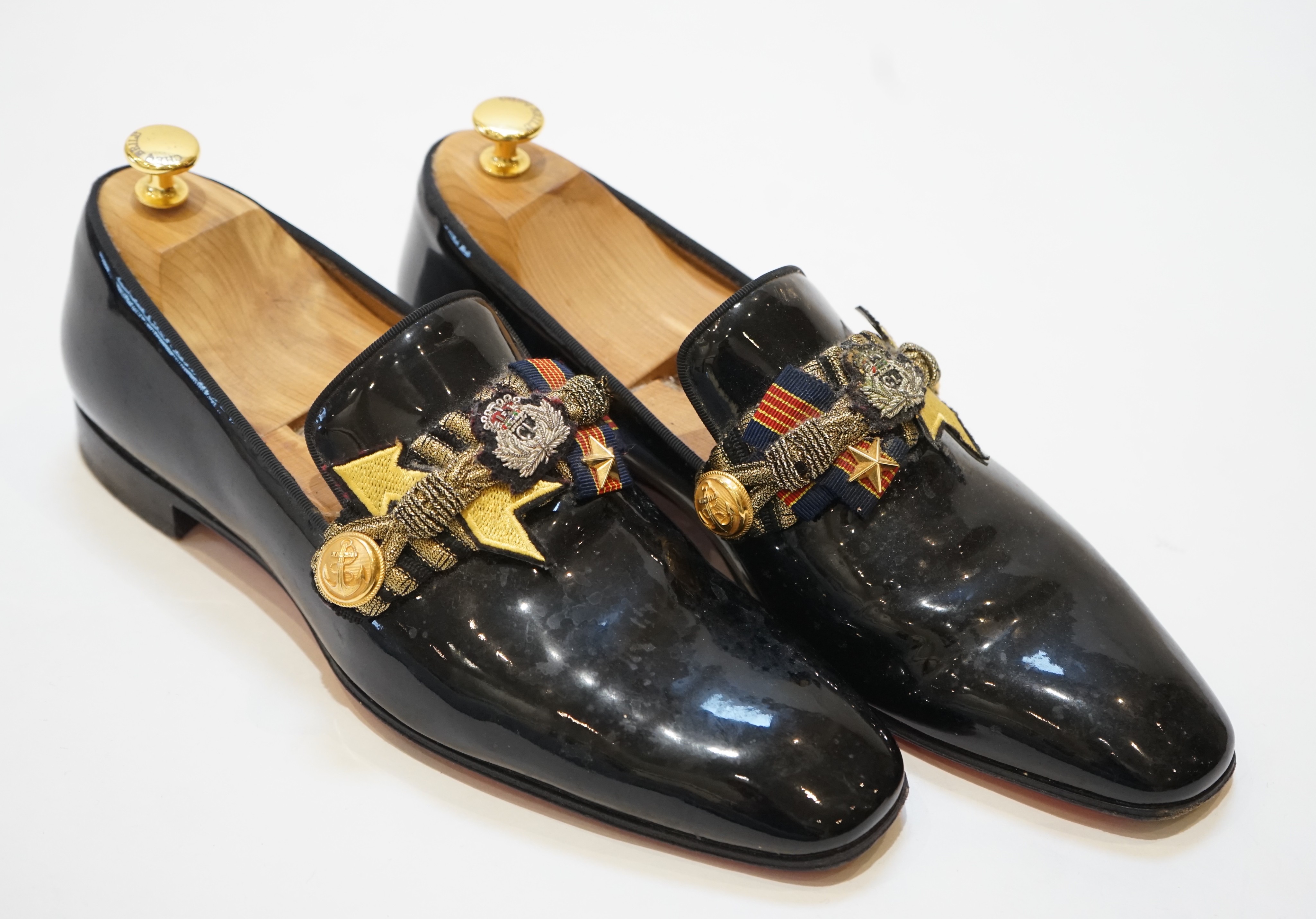 A pair of gentleman's Christian Louboutin patent leather dress shoes with applied and embroidered crests, size 43, in bag